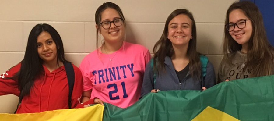 Melanny+Bastidas%2C+Maria+Edwarda+Rodrigues-Ferreira%2C+Livia+Pratera%2C+and+Nicole+Schabarum+pose+with+flags+from+Ecuador+and+Brazil.