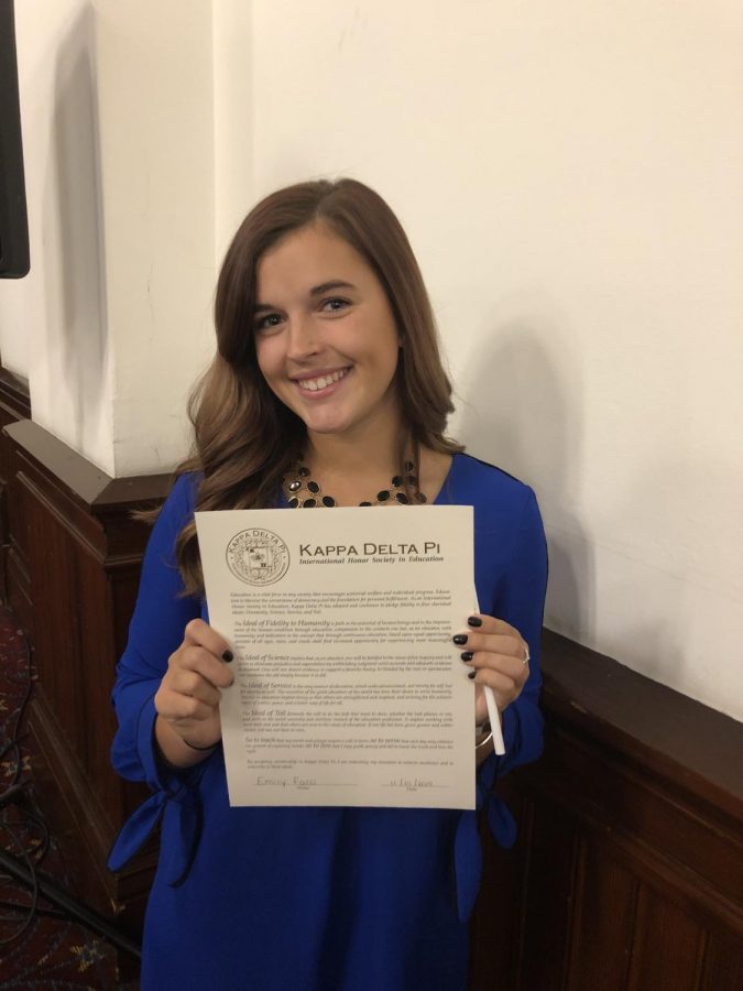 Miss Facci smiles with pride while holding her paper from the International Honor Society. She received this paper from the education department.