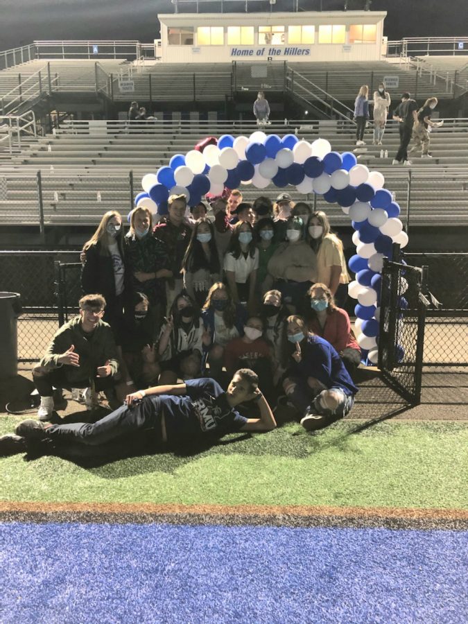 Some Seniors celebrate with a picture underneath the blue and white balloon archway.