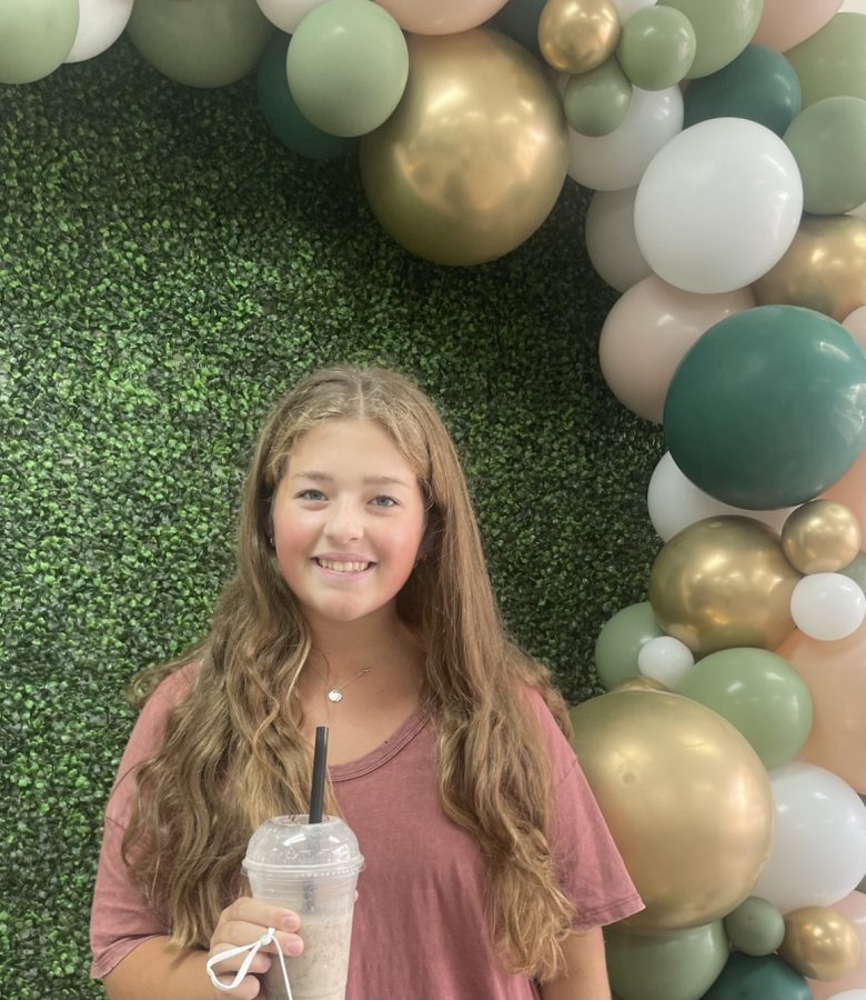 Emma Bowman poses with the picture wall featured in The Nutrition Fix. The colorful balloons match the bright sprinkles in the shake!