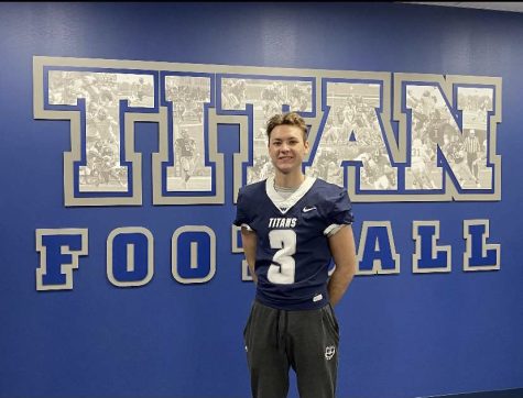 Connor Roberts poses for a picture in his future jersey in front of the “Titans Football” wall at Westminster College. He is excited to start his college career this fall!