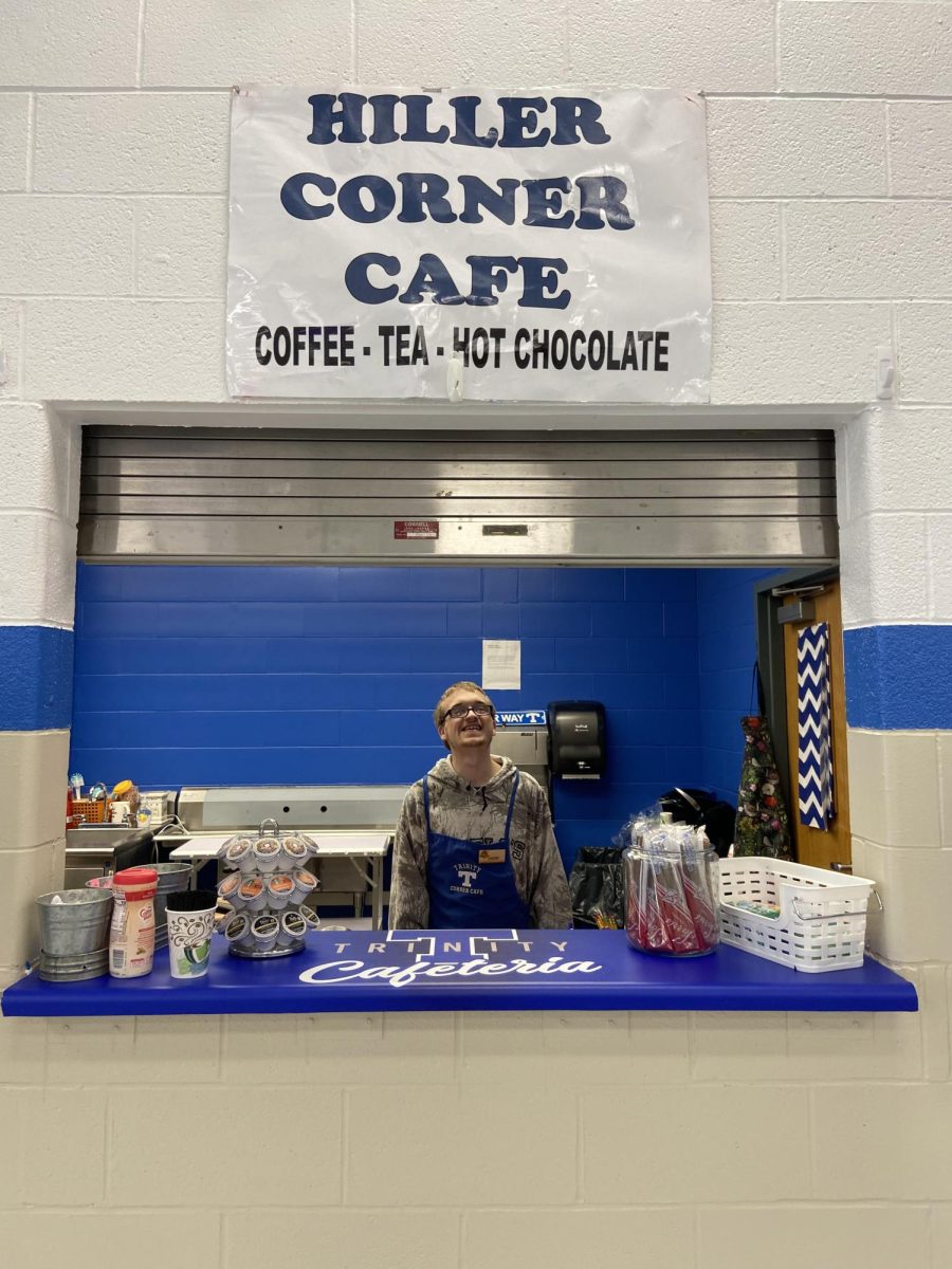 Proudly wearing his apron, student Nolan Beckett stands ready to serve his fellow students. The Hiller Cafe workers are ready to get to work in the new coffee stand.