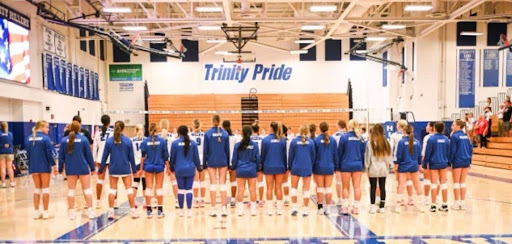 The team is standing for the National Anthem together at the Trinity High School gymnasium before their game.
